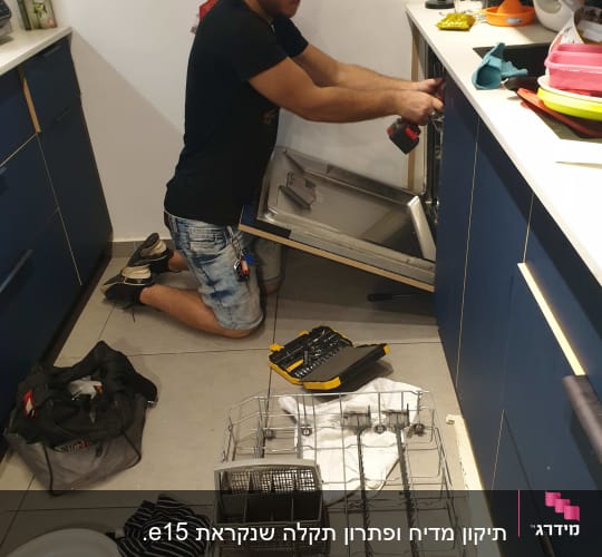 אדם מתקן מדיח כלים עם מברגה חשמלית